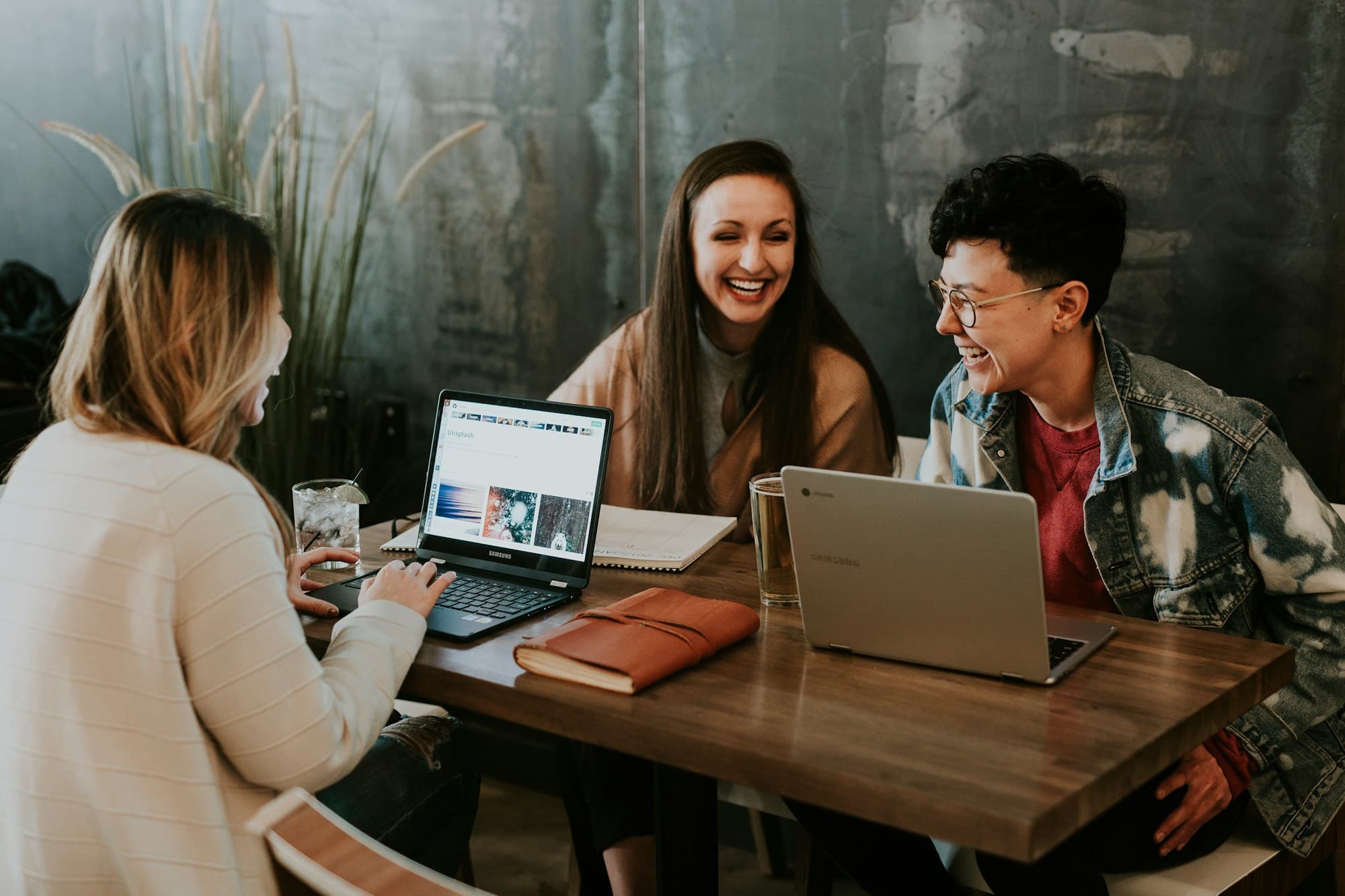Three technology professionals talking and laughing around their laptops