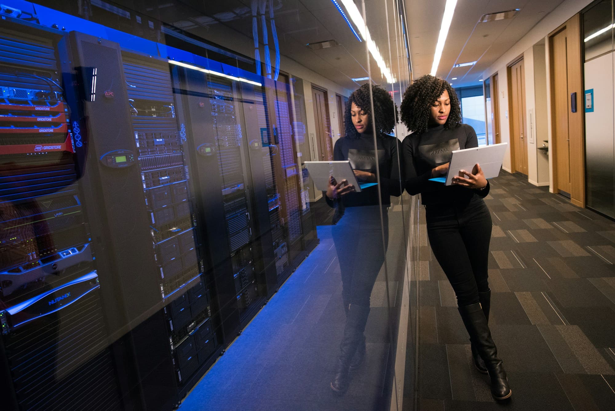 Two technology professionals with laptops walking through a data centre